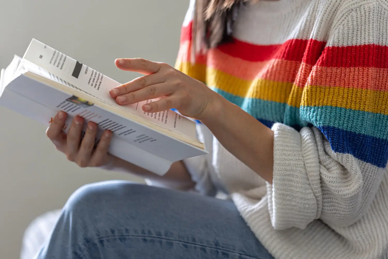 close-up-open-book-hands-girl-bright-colored-sweater